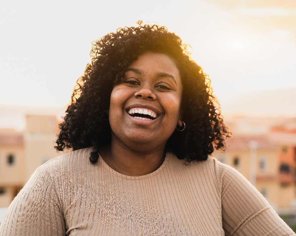 Black woman smiling in the sunlight after therapy for racial trauma in NJ