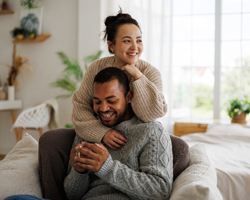 Inter-racial couple hugging in their living room